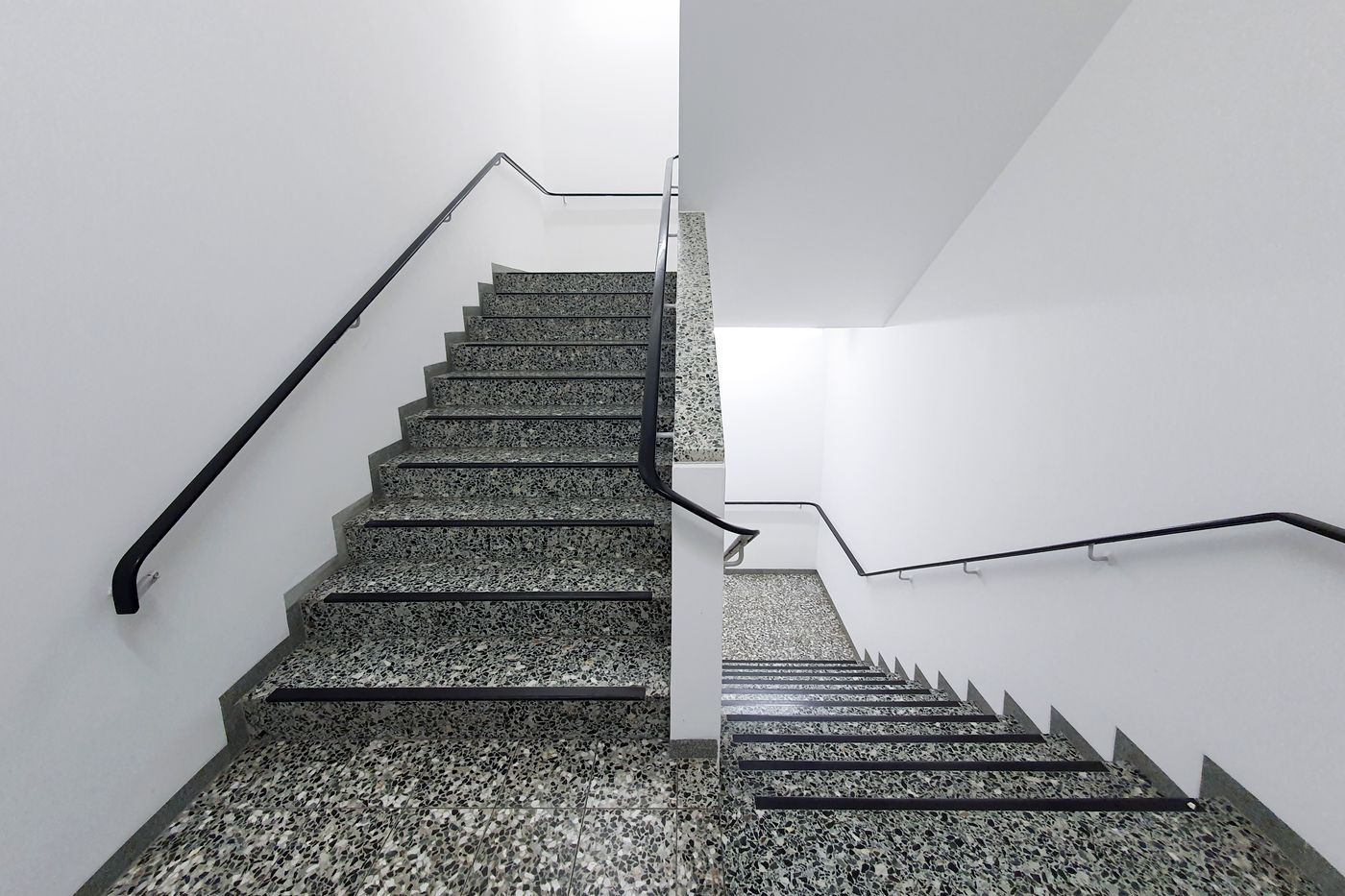 Sauberes Treppenhaus mit Terrazzostufen und Handlauf